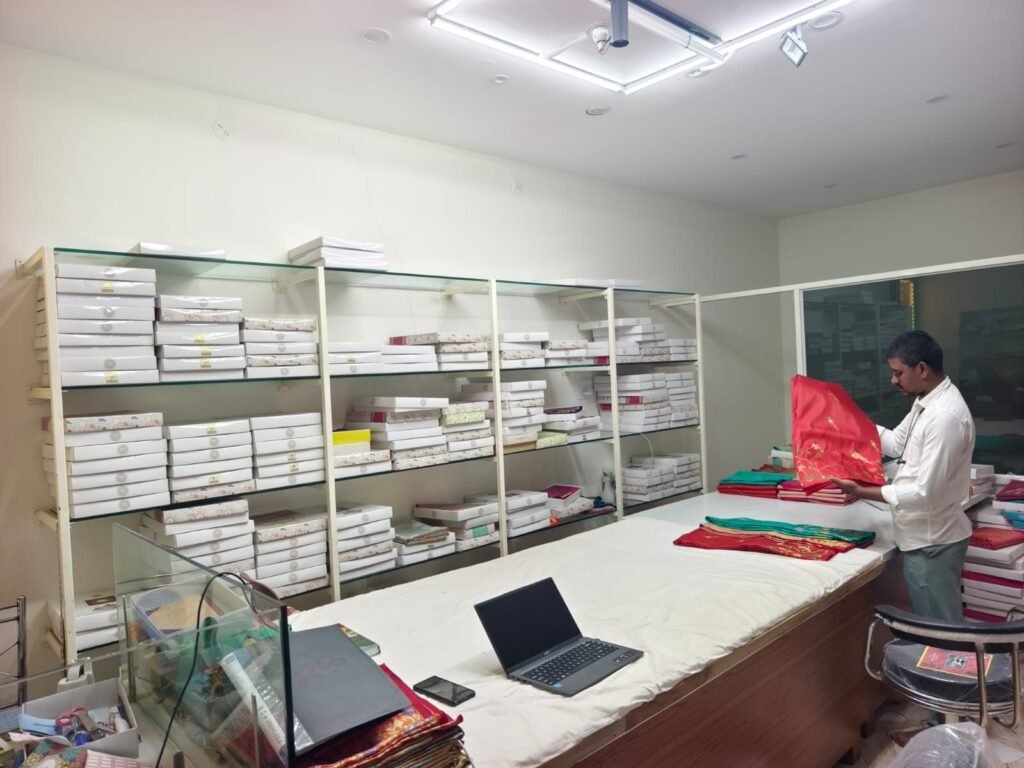 Ramanji Handlooms staff presenting a red silk saree at the showroom counter