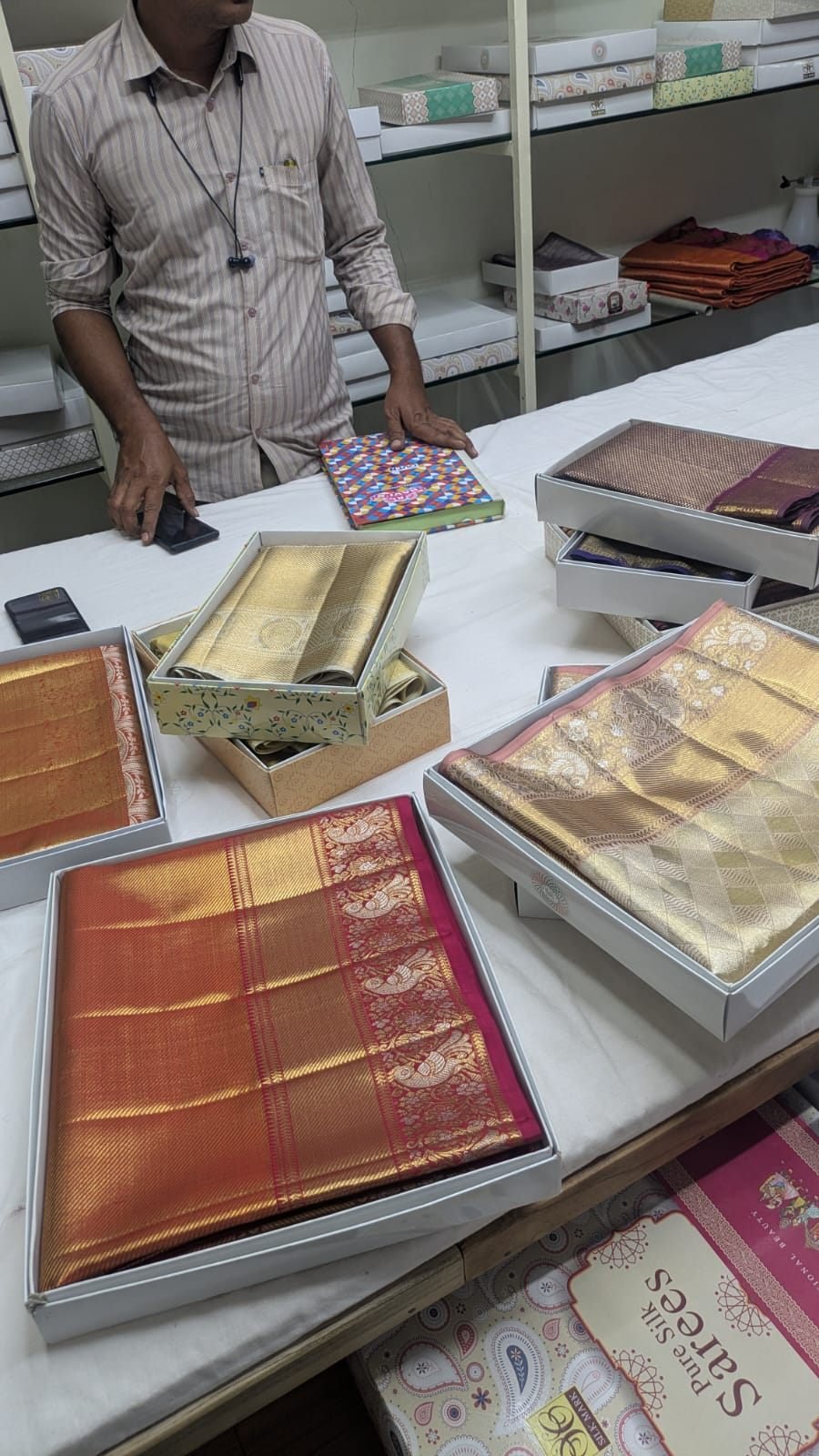 Ramanji Handlooms staff member presenting sarees at the showroom counter, Dharmavaram